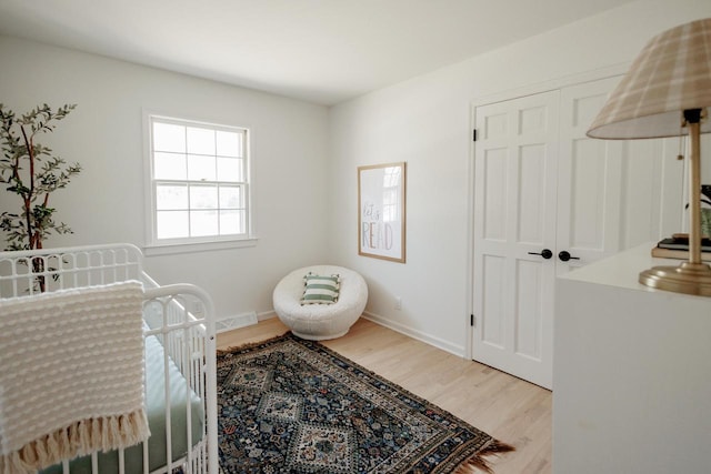 bedroom featuring visible vents, baseboards, light wood-type flooring, and a closet