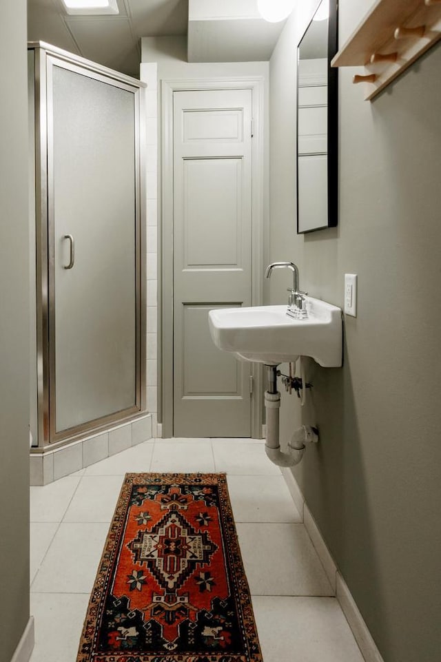 bathroom with tile patterned flooring, a stall shower, baseboards, and a sink