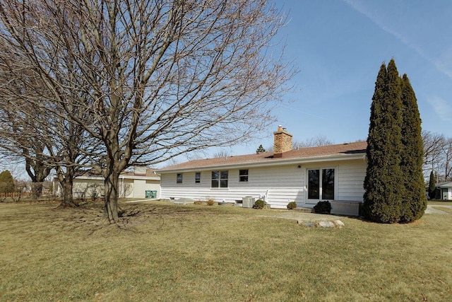 rear view of property featuring a yard, central AC unit, and a chimney