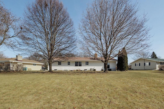 back of house featuring a lawn and a chimney