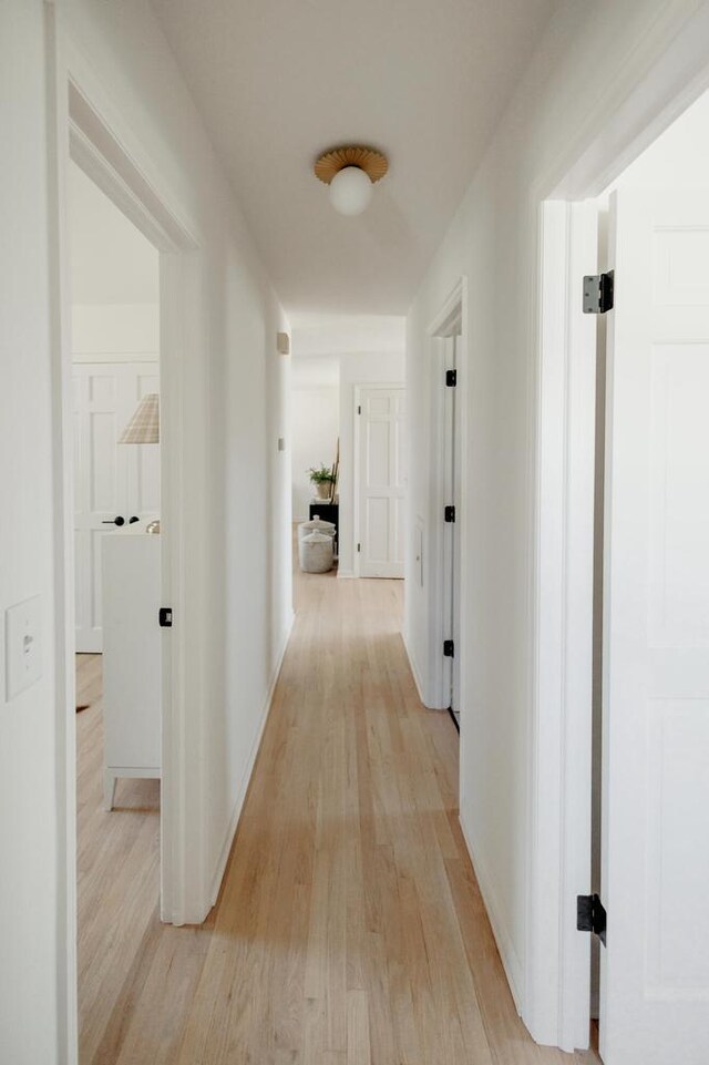 hall with light wood-style flooring and baseboards