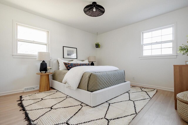 bedroom featuring visible vents, multiple windows, baseboards, and light wood-style flooring