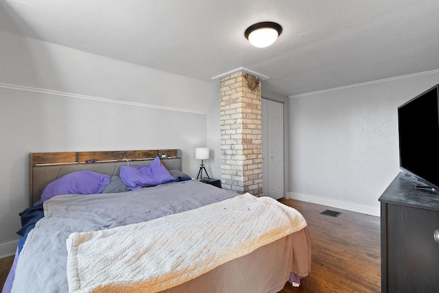 bedroom featuring visible vents, baseboards, dark wood-style flooring, and ornate columns