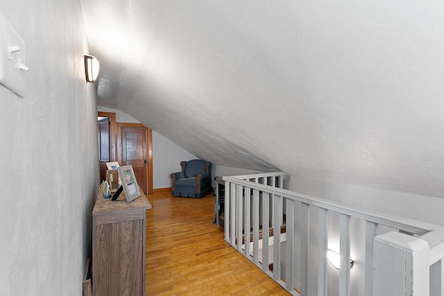 corridor featuring lofted ceiling and light wood-style floors