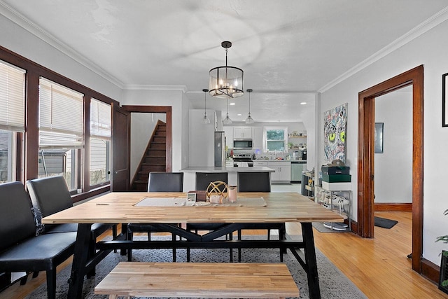 dining room featuring light wood-type flooring, an inviting chandelier, crown molding, baseboards, and stairs