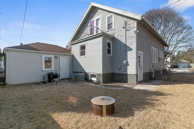 rear view of property featuring a lawn, central AC, a balcony, and fence