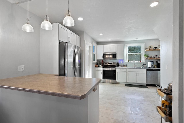 kitchen with a sink, stainless steel appliances, a peninsula, and white cabinetry