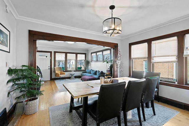 dining space with an inviting chandelier, baseboards, light wood-style floors, and ornamental molding