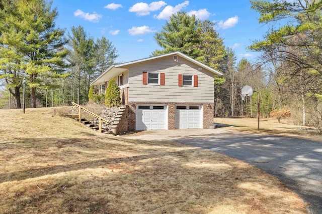 view of property exterior with stairs, brick siding, an attached garage, and driveway