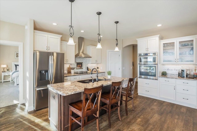 kitchen featuring decorative backsplash, white cabinetry, appliances with stainless steel finishes, and wall chimney range hood