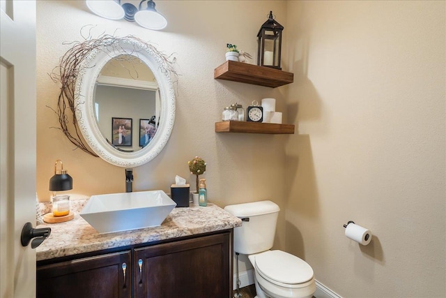 half bathroom with toilet, vanity, and baseboards