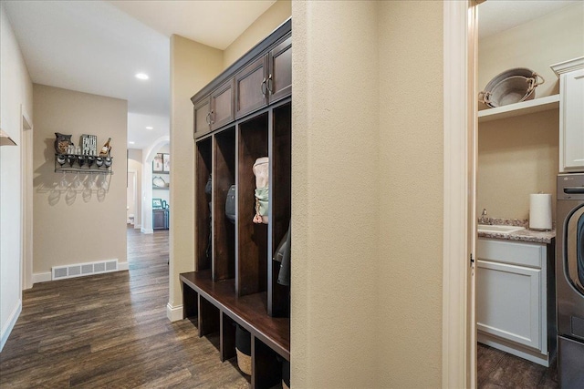 mudroom featuring visible vents, baseboards, dark wood finished floors, arched walkways, and a sink