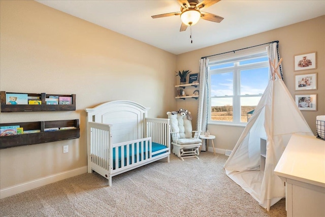 carpeted bedroom with a nursery area, baseboards, and ceiling fan