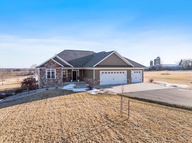 view of front of house with an attached garage, stone siding, and driveway