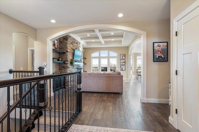 living area featuring baseboards, coffered ceiling, dark wood finished floors, a fireplace, and beamed ceiling