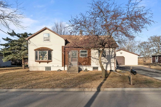 view of front of house featuring aphalt driveway, a front lawn, and an outdoor structure