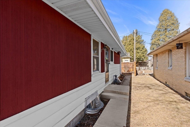 view of side of home with brick siding and fence