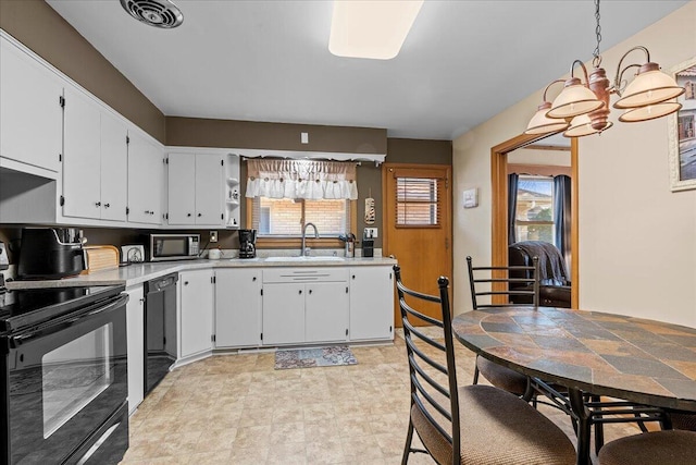 kitchen featuring visible vents, light countertops, white cabinets, black appliances, and a sink