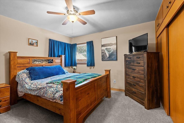 bedroom with baseboards, a ceiling fan, a closet, and light carpet