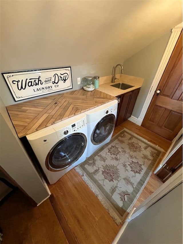 laundry room featuring a sink, cabinet space, washing machine and dryer, and wood finished floors