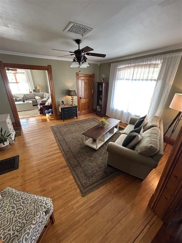 living area featuring visible vents, hardwood / wood-style floors, and crown molding