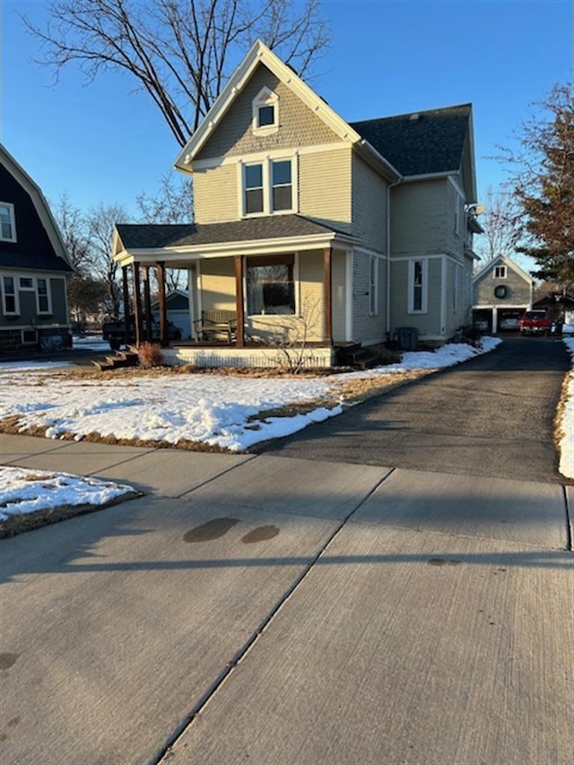 victorian home with a porch, a shingled roof, and driveway