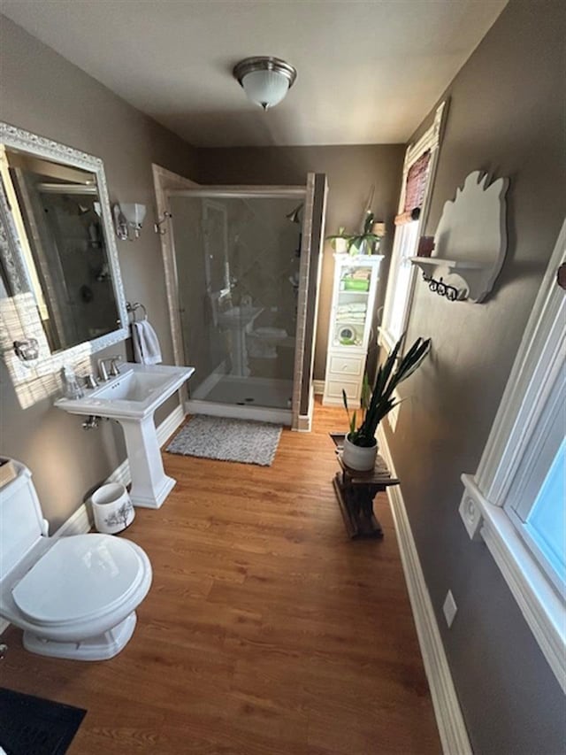 bathroom featuring a stall shower, toilet, baseboards, and wood finished floors