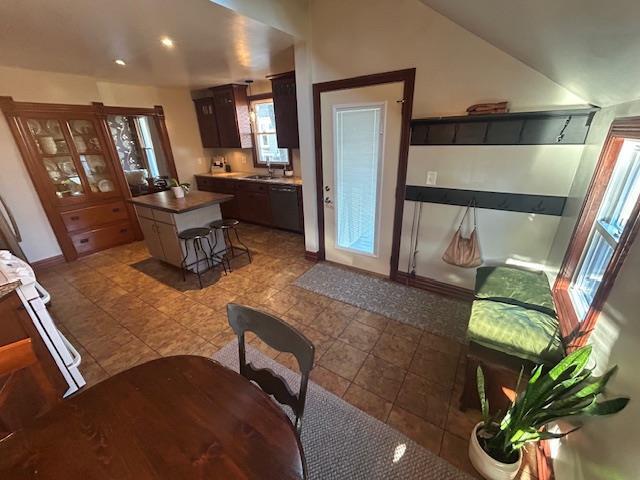 kitchen with dark countertops, a center island, a kitchen bar, lofted ceiling, and a sink