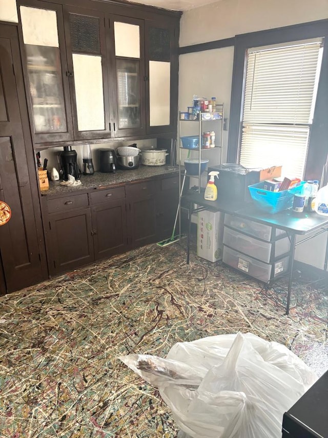 kitchen featuring dark countertops, dark brown cabinets, and glass insert cabinets