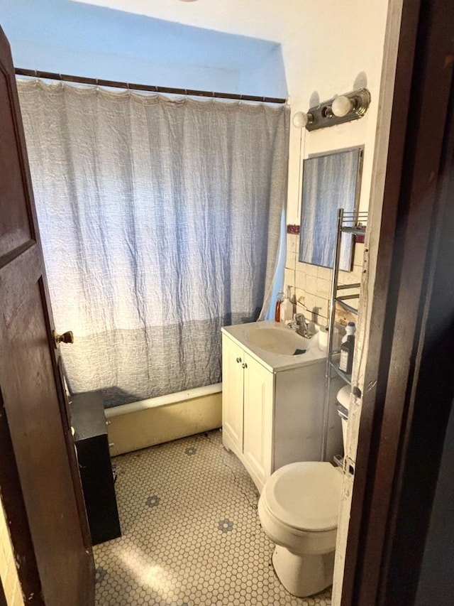 full bath featuring tile patterned floors, toilet, curtained shower, tile walls, and vanity