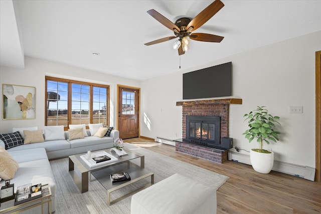 living room with wood finished floors, a fireplace, ceiling fan, a baseboard heating unit, and baseboard heating