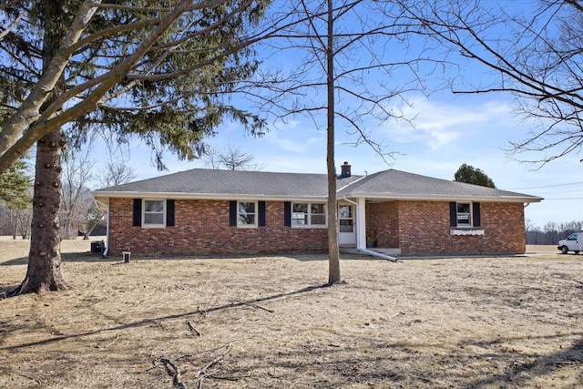 single story home with brick siding, a chimney, and a shingled roof