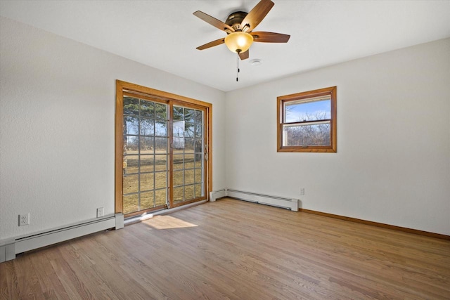 spare room with a baseboard heating unit, wood finished floors, and a wealth of natural light