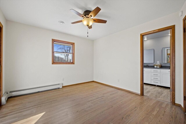 unfurnished bedroom featuring light wood-style flooring, ensuite bathroom, baseboards, and baseboard heating