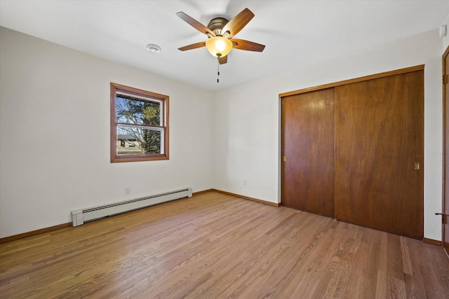 unfurnished bedroom featuring wood finished floors, a closet, baseboards, baseboard heating, and ceiling fan