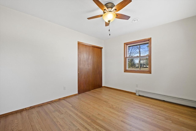 spare room featuring baseboards, a ceiling fan, light wood-style floors, and a baseboard radiator