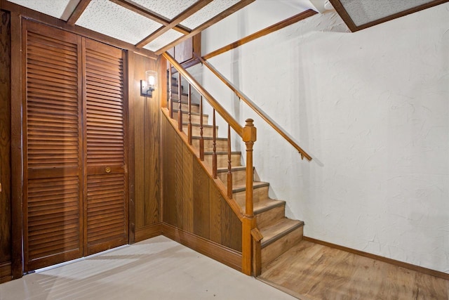 staircase featuring wood finished floors and a textured wall