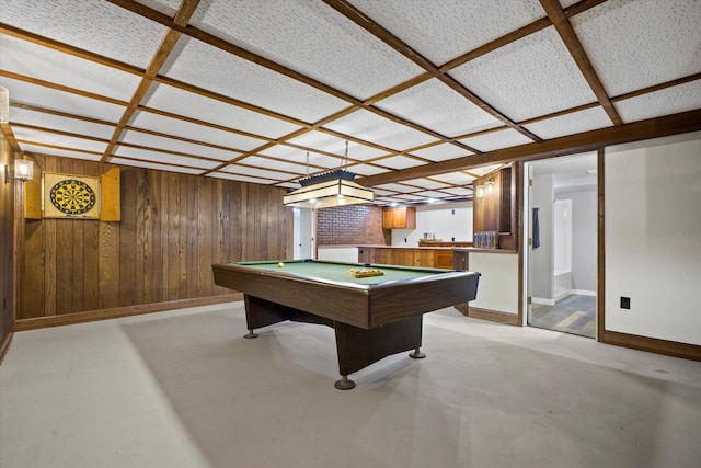 rec room with coffered ceiling, baseboards, wood walls, and finished concrete floors