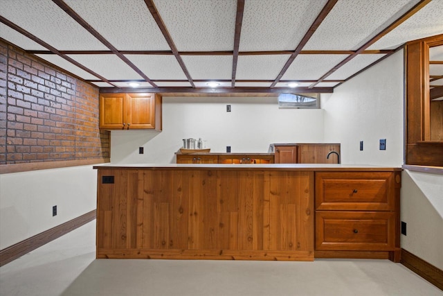 kitchen with baseboards, brown cabinets, and concrete flooring