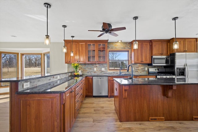 kitchen with decorative backsplash, brown cabinets, appliances with stainless steel finishes, and a sink