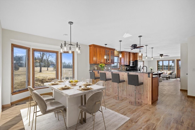 dining room featuring visible vents, light wood-style flooring, a ceiling fan, and baseboards