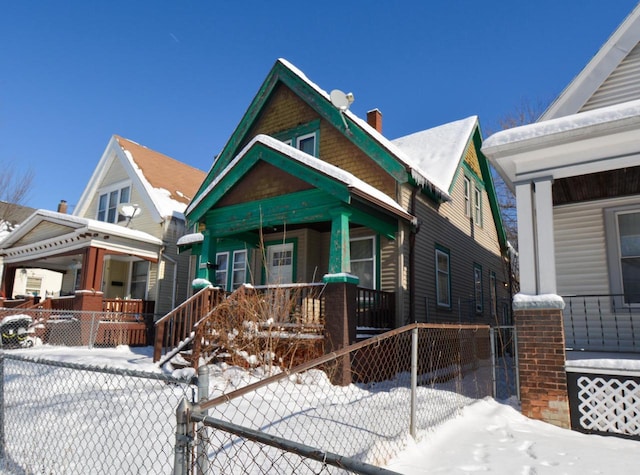 view of front of home featuring covered porch, a fenced front yard, and a chimney