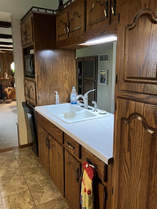 kitchen featuring visible vents, a sink, light countertops, black microwave, and dishwasher