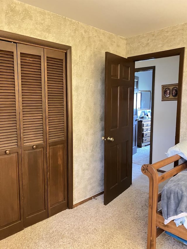 carpeted bedroom with a closet and a textured wall