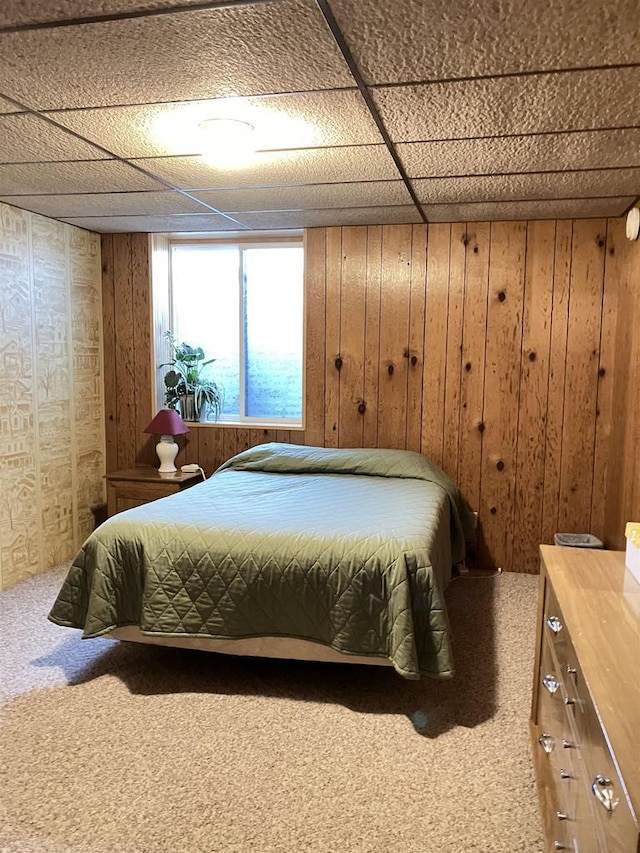 carpeted bedroom featuring a paneled ceiling and wooden walls