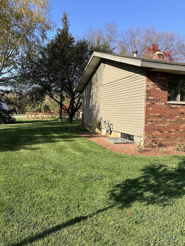 view of side of home featuring a lawn and brick siding