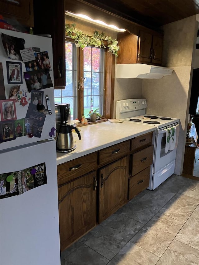 kitchen featuring under cabinet range hood, white appliances, and light countertops