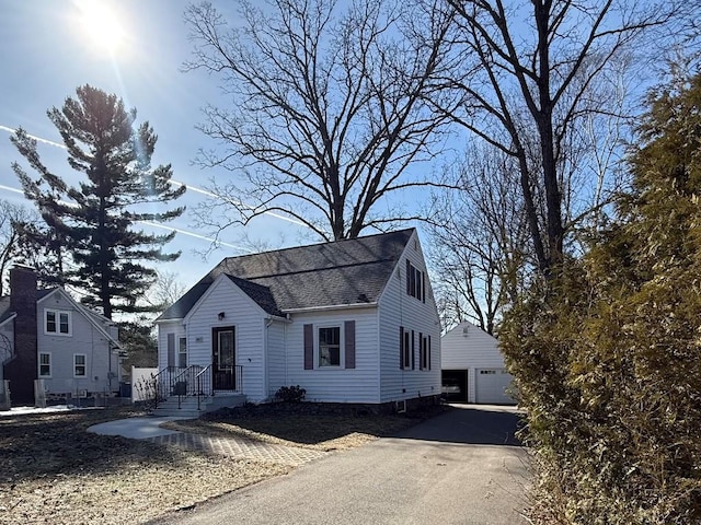 view of front of house featuring an outbuilding, a garage, and roof with shingles