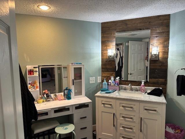 bathroom with vanity, wooden walls, and a textured ceiling