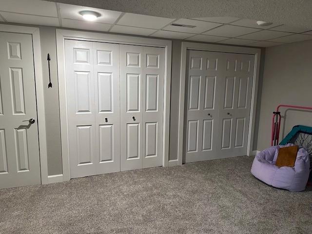 interior space featuring carpet flooring, a paneled ceiling, and baseboards